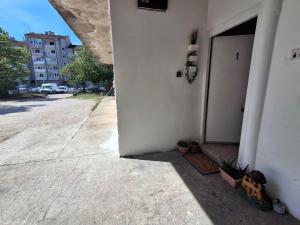 a white building with a door and plants on the sidewalk at Benkovac sobe in Benkovac