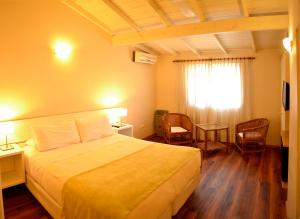 a hotel room with a bed and chairs and a window at La Posada Hotel in Pinamar +18 photos