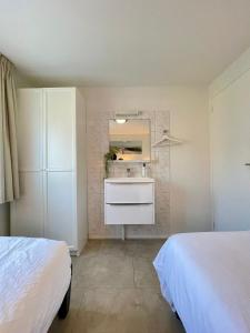 a white bathroom with a sink and a mirror at De Snip in Ballum