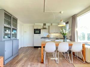 a kitchen with a wooden table and white chairs at De Snip in Ballum