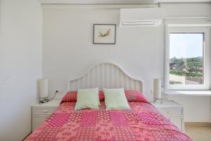 a bedroom with a bed with a pink comforter and a window at Golf Mar I H5 in Pals +24 photos