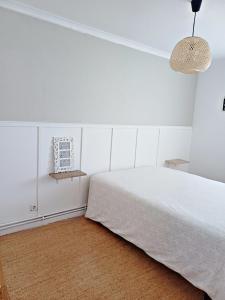 a white bedroom with a bed and a lamp at La Dama Boba in Olmedo