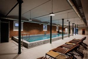 a pool in a building with benches and a table at Hotel Atrium in Târgu Secuiesc