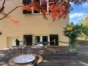 a wooden table with two glasses and a vase with flowers at Cocon nature - Appartement 1 chambre - 4 personnes in Berstett