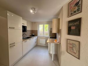 a small kitchen with white cabinets and a window at Cocon nature - Appartement 1 chambre - 4 personnes in Berstett