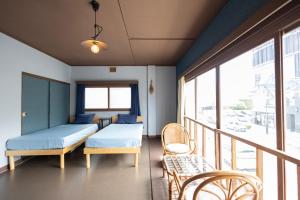 a room with two beds and a balcony with chairs at KARASUYA GuestHouse in Takasaki