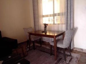 a dining room table with two chairs and a window at Raah residence in Nairobi