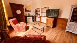 a living room with a couch and a television at La Maison du Rosier in Saint-Honoré-les-Bains