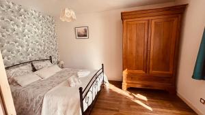 a bedroom with a bed and a wooden cabinet at La Maison du Rosier in Saint-Honoré-les-Bains