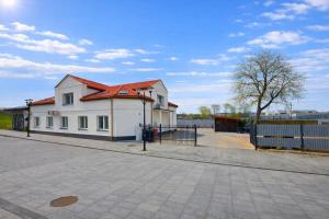 a white house with a red roof on a street at Apartamenty Nad Pilicą - Klimatyzacja - Sulejów in Sulejów