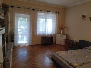 a bedroom with a bed and two large windows at Györkös Apartman in Balatonszárszó
