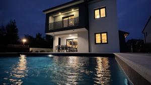 a house with a swimming pool in front of a house at Villa Dani by Villas Guide in Gostinjac