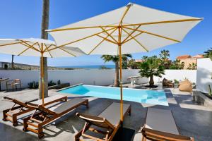 a patio with chairs and umbrellas next to a swimming pool at Casa Alisios Sea View Villa private Infinity Pool Sunsets in La Pared