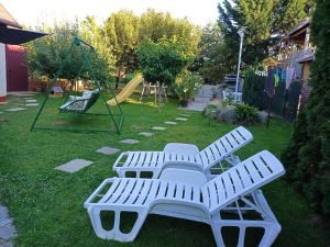 a white bench in a yard with a playground at Györkös Apartman in Balatonszárszó +1 photo