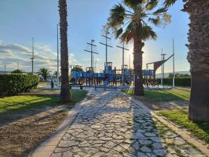 a park with a playground with palm trees at Notre location au Barcarès in Le Barcarès