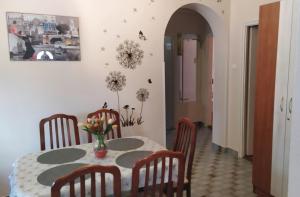 a dining room table with chairs and a vase of flowers on it at Györkös Apartman in Balatonszárszó