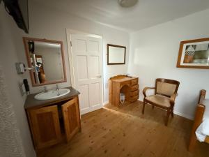 a bathroom with a sink and a mirror and a chair at Kerry Ocean Lodge Room only in Glenbeigh