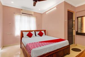 a bedroom with a bed with red pillows and a window at Hotel O RD CONVENTIONS in Visakhapatnam