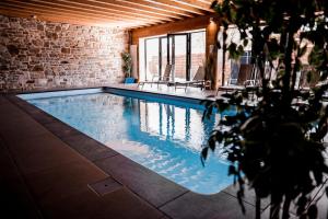 a swimming pool with chairs and a brick wall at Le Pays des Sources in Waimes
