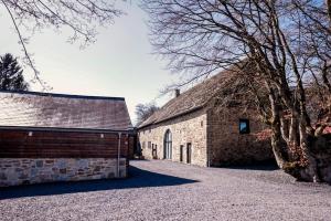 an old brick barn with a tree next to it at Le Pays des Sources in Waimes