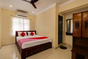 a bedroom with a bed with red pillows and a window at Hotel O RD CONVENTIONS in Visakhapatnam