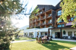 a person sitting at a table in front of a building at Hotel Tyrol in Funes