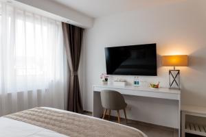 a bedroom with a bed and a desk with a television at Hotel Grand Asia in Walferdange