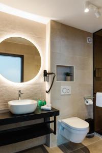 a bathroom with a sink and a toilet and a mirror at Hotel Grand Asia in Walferdange