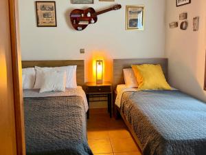 a bedroom with two beds and a guitar on the wall at Lithos House in Monólithos