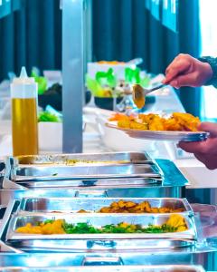 a buffet line with plates of food and a person holding a spoon at Plaza Inn Hotel in Doha +10 photos