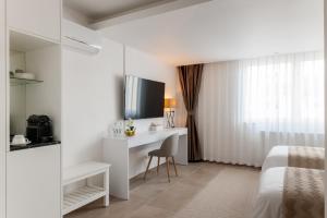 a bedroom with a bed and a desk and a television at Hotel Grand Asia in Walferdange