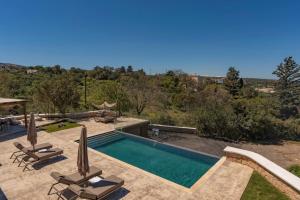 a swimming pool with two lounge chairs and a swimming poolvisor at Sunny Villa-Earthen Stone Gem by etouri in Margarítai