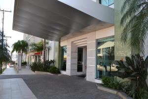 an external view of a building with palm trees at Hotel Guest in Venâncio Aires