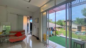a living room with a couch and a large window at Mae Wad House in Ban Oi