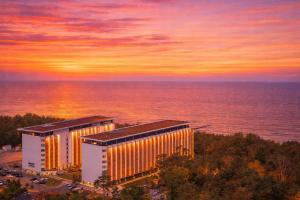 two buildings in front of the ocean at sunset at Prestige 103 - z widokiem na morze - BASEN, sauna, jacuzzi w cenie pobytu! - Easy - Rent Apartments in Pobierowo
