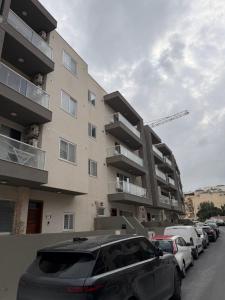 a parking lot with cars parked in front of a building at Marija Block St Julian's Apartments in Is-Swieqi