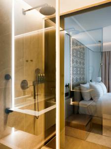 a glass shower in a bedroom with a bed at Boutique Hotel Venturo, a Member of Design Hotels in Split