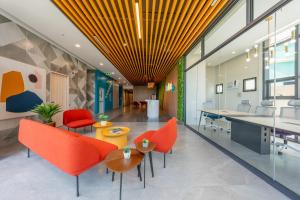an office lobby with orange chairs and tables at ABC Plus Hotel & Homes in Cebu City +40 photos
