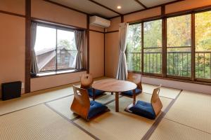 a room with a table and chairs and windows at Anto Azumino in Azumino
