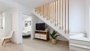 a living room with a staircase and a television at Casa Playa Torrecilla by South Costa in Nerja