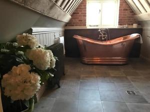 a large bathroom with a copper tub and flowers at Broad Leys in Aylesbury