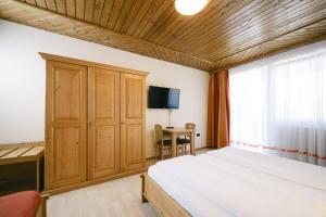 a bedroom with a bed and a desk and a television at Pension Seehof in Holzöster