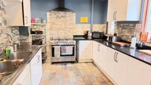 a kitchen with white cabinets and a stove top oven at Lledr House Hostel near two Zip World sites in Dolwyddelan