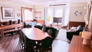 a living room with a table and a piano at Lledr House Hostel near two Zip World sites in Dolwyddelan