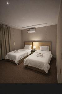 a hotel room with two beds and a lamp at شاليهات حديقة الوسام لبيوت العطلات 1 in Taif