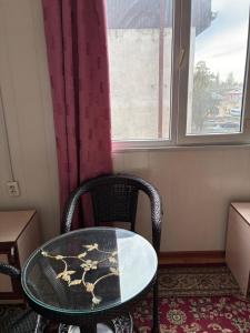 a table and a chair in a room with a window at Жетиген in Karakol