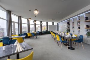 a dining room with tables and chairs and windows at Hotel Kristály Konferencia & Wellness in Ajka
