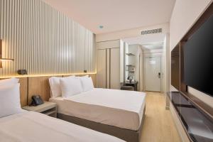 ein Hotelzimmer mit zwei Betten und einem Flachbildfernseher in der Unterkunft Waveside hotel in Altınordu