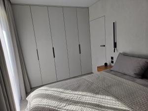 a bedroom with a bed and white cabinets at Apartaments Jaunyste Free parking, Self Check - in in Klaipėda