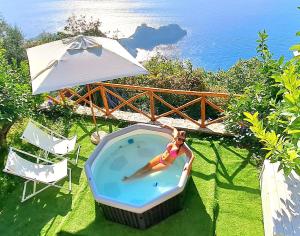 a woman in a swimming pool with an umbrella at Sea View Apartments Amalfi Coast by Amalfi Coast with Locals in Conca dei Marini